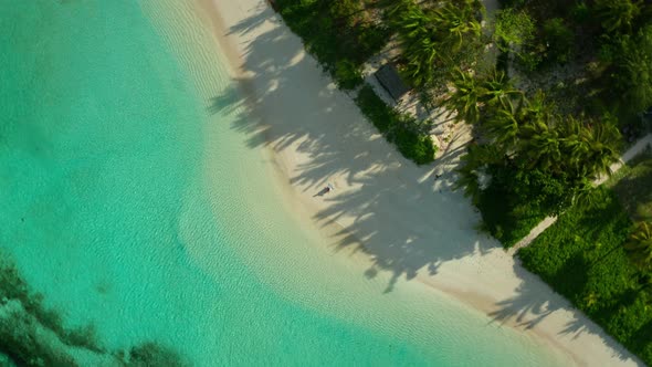 Remote tropical island with woman enjoying a perfect white beach by herself alt