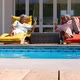 Front view of black senior couple relaxing on pool deck chair in back yard of their home 4k - VideoHive Item for Sale