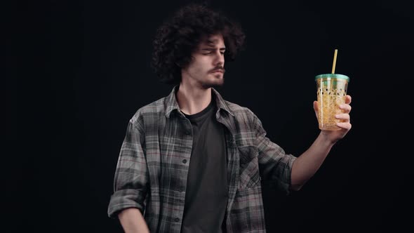 The Charismatic Young Man Holds a Straw Glass in One Hand Points to Him Satisfied and Smiling Puts alt