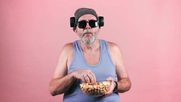 Mature trendy man in sunglasses eating popcorn. alt