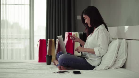 stressed woman using laptop for online shopping on a bed