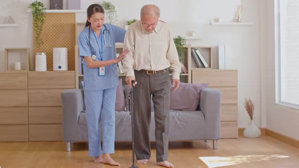 Beautiful doctor helping old man at clinic. Holding a senior patient with walking stick. Elder man u alt