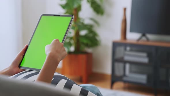 woman holding in hands a digital tablet with green screen for internet online. alt