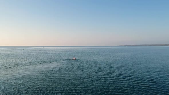 Moving Aerial Shot of Man Swimming Freestyle in Blue Sea