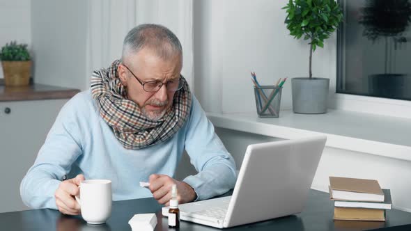 A Sick Person Sits at a Table at Home and Suffers From the Flu and a High Fever