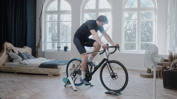 Side View of a Cyclist Training on an Exercise Bike Staying at Home