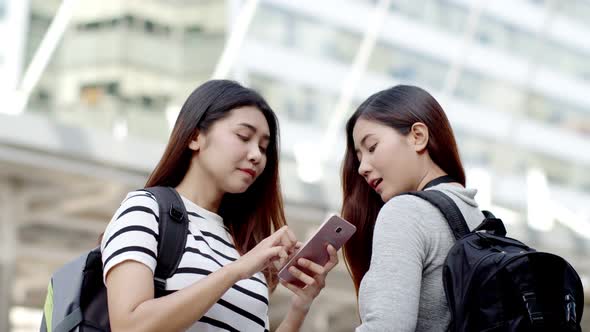 Two backpacker teenager female searching location on smartphone alt