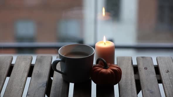 Cup of coffee and pumpkin with candle on wooden table