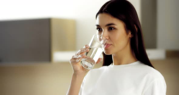 Brunette Drinks Mineral Sparkling Water From a Glass
