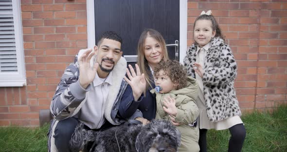 Happy multiracial family looking at camera, smiling and waving with hands