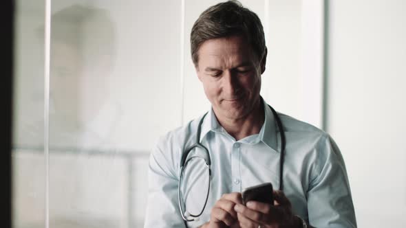 Mature Adult Male Doctor in Hospital using smart phone