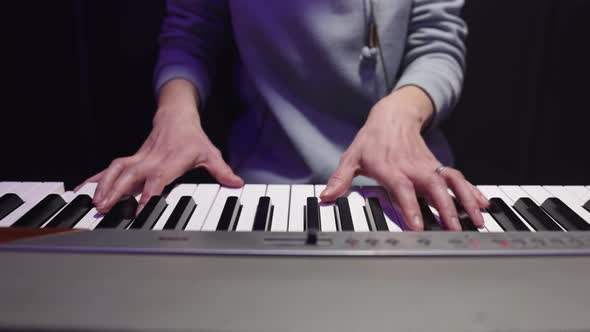 Close up female hands playing musical keys in studio.