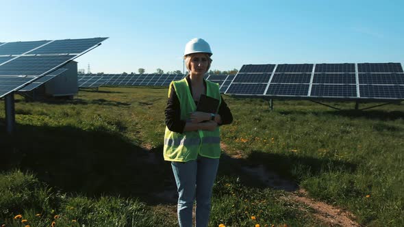 Industrial Woman Engineer in Uniform Walking Through Solar Panel Field for Examination