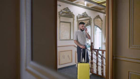 Wide Shot Reflection in Mirror of Luxurious Hotel of Confident Young Man Talking on the Phone alt
