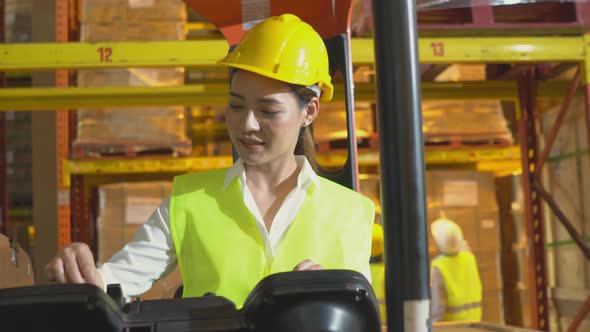 Portrait of Asian warehouse worker driving forklift