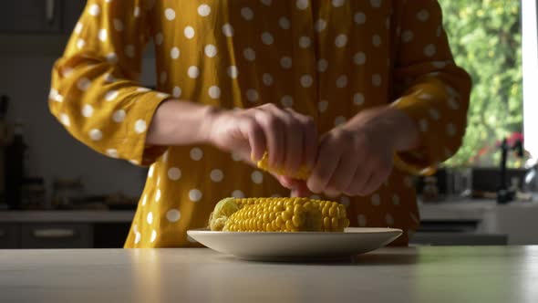 woman rubs salt on corn at kitchen