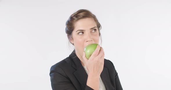 Woman biting and eating an apple on a white studio background alt