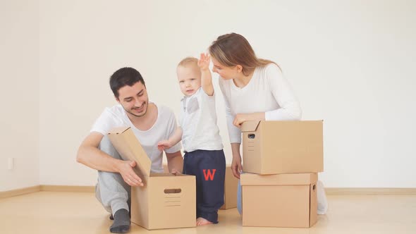 Family with Boy Unpacking Moving Cardboard Boxes at New Home alt