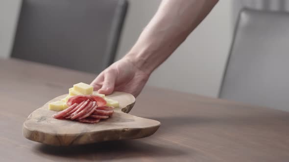 Slow Motion Man Put Olive Board with Vintage Cheese and Salae on Walnut Table alt
