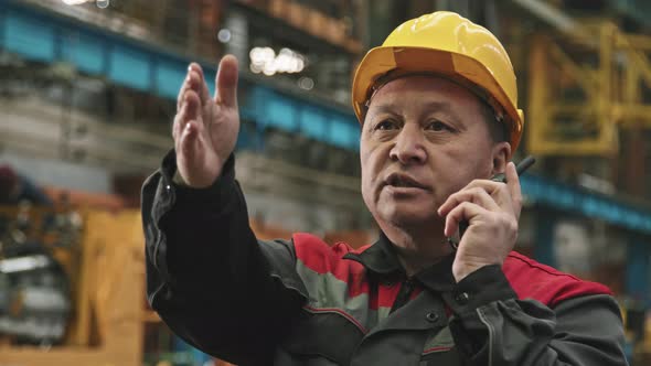 Asian Plant Supervisor Talking On Walkie-Talkie alt
