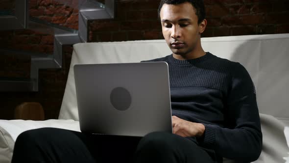 Handsome African Man Typing on Laptop at Night alt