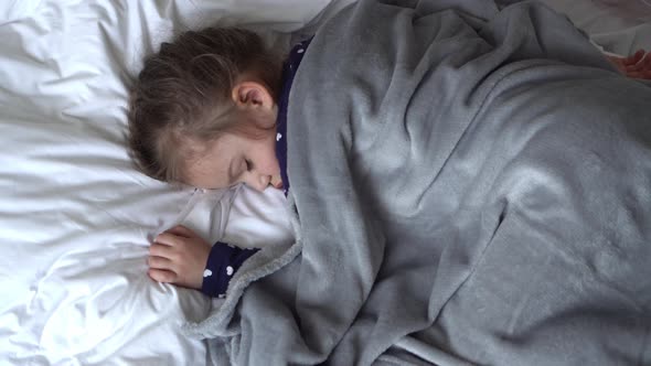 Authentic Cute Little Girl Sleeping Sweetly In Comfortable White and Grey Bed Middle Plan alt