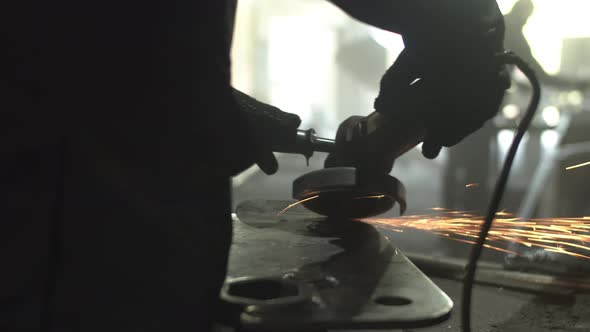 Unrecognizable Male Employee Grinding Metal on Workbench