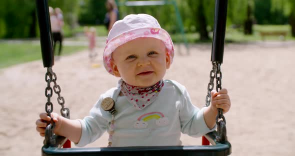 Baby girl playing on swing alt