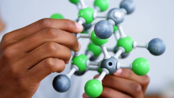 Schoolboy experimenting molecule model in laboratory at school alt