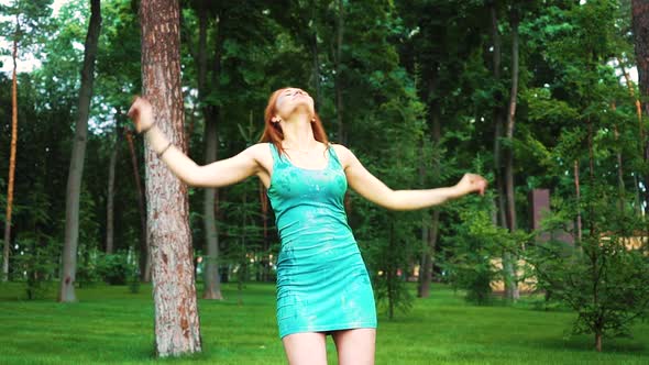 red haired girl in Holi paints dances in green park in slow motion alt