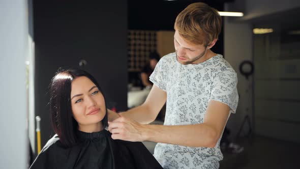 Beautiful Brunette Woman Customer Laugh in a Beauty Salon While Talking To Young Male Hairdresser alt