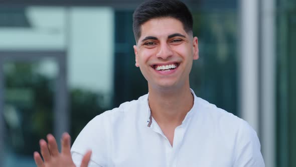 Young Positive Indian Blogger Standing Outdoors Wave Hand Greeting Subscriber Start Speech Looks at alt