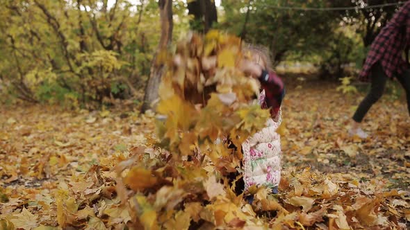 The Mischievous Little Girl Merrily Plays in a Big Pile of Yellow Foliage