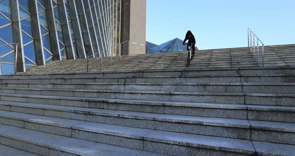 Woman free rider riding bike going down city stairs alt