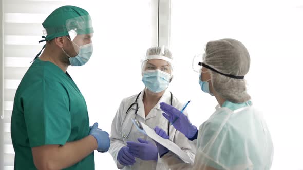 Two Doctors in Protective Uniforms Are Discussing Something and Giving Directions To the Nurse alt