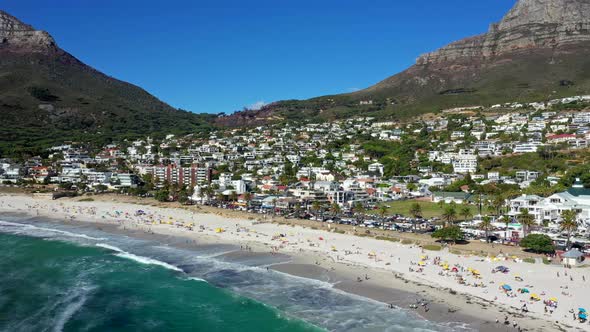 Wide aerial view of Camps Bay beach filled with a ton of beachgoers