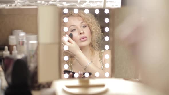 Blonde Looking at Mirror and Doing Makeup at Home alt