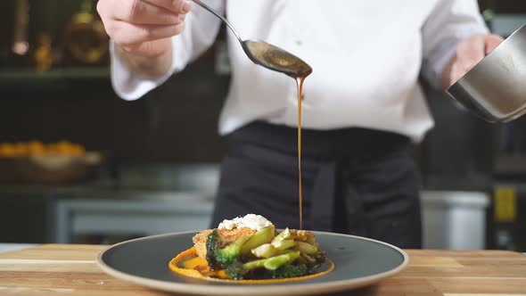 Closeup of a Gourmet Dish the Chef Pours Sauce Over Cutlets with Pumpkin Puree and Broccoli on a