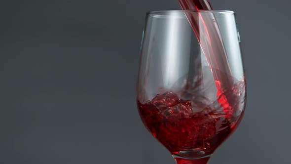 Pouring Red Wine in Super Slow Motion on Grey Background alt