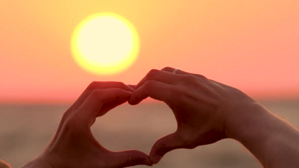 Symbol of Love, Feelings. New Beginning. Morning Summer Sun and Heart Made By Hands. Closeup of alt