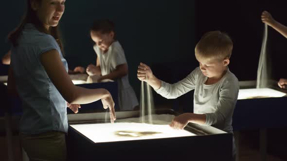 Woman Teaching Kids How to Do Sand Animation alt