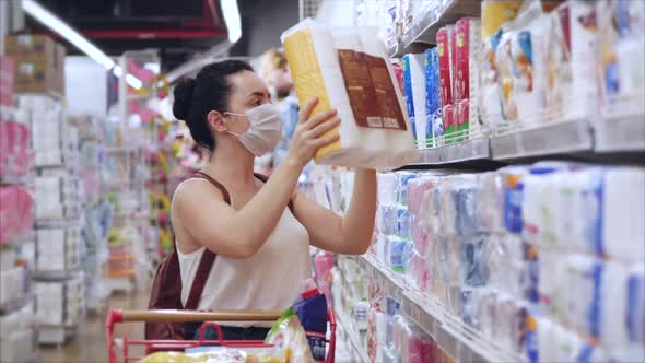Young Woman in a Mask From a Coronavirus Epidemic Stands in the a Supermarket, Where People Are in a alt