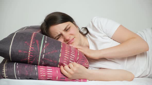 A Woman Tries to Fall Asleep Rubs a Sore Neck and Lies Down on a Comfortable Orthopedic Pillow alt