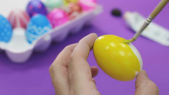 Happy Easter Close Up. White man painting a yellow Easter egg with a brush