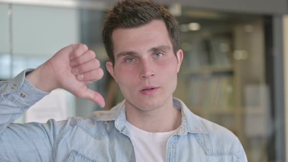 Portrait of Unhappy Young Designer Showing Thumbs Down alt