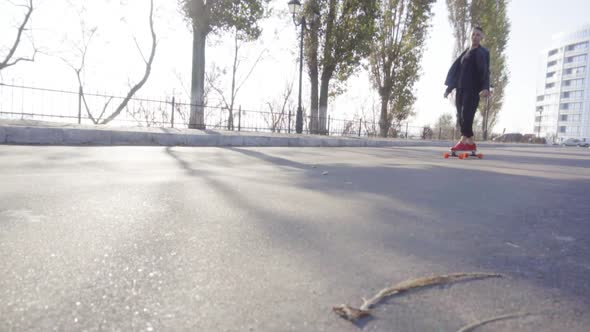 Young Man Skates on His Longboard on the Road in the City alt