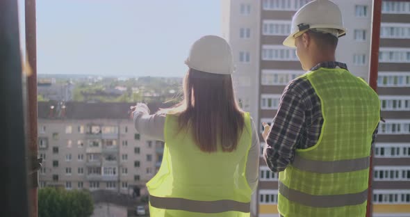 Back Turned Architect and Technician at Construction Site Reviewing Office Blueprints alt