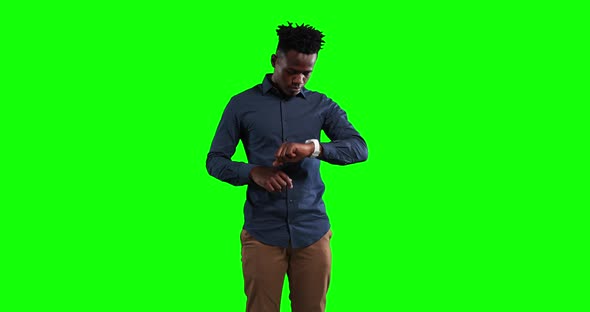 an African American man checking his smartwatch in a green background