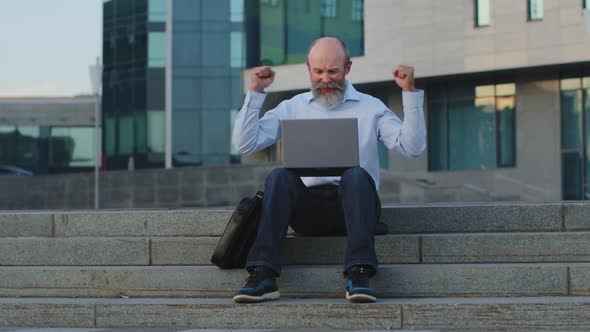 Old Grandfather Retirement Age Looking at Laptop Monitor Waves Hands Feeling Happiness Rejoicing alt