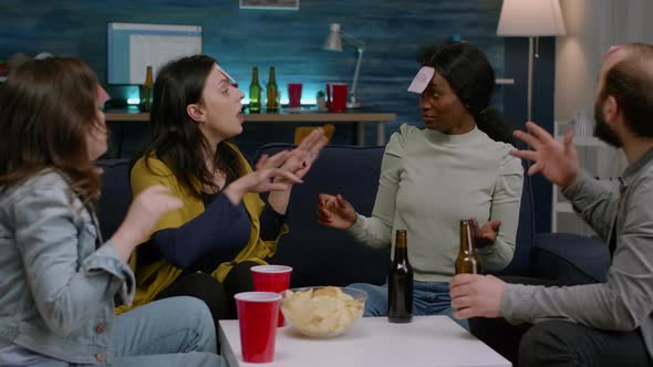 Multiracial Friends Laughing While Playing Together Board Game Using Sticky Notes alt